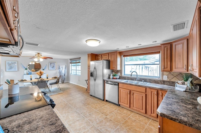 kitchen featuring decorative backsplash, visible vents, dark countertops, a sink, and stainless steel appliances