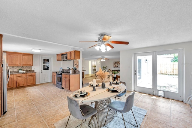 dining space with light tile patterned floors, ceiling fan, french doors, and a textured ceiling