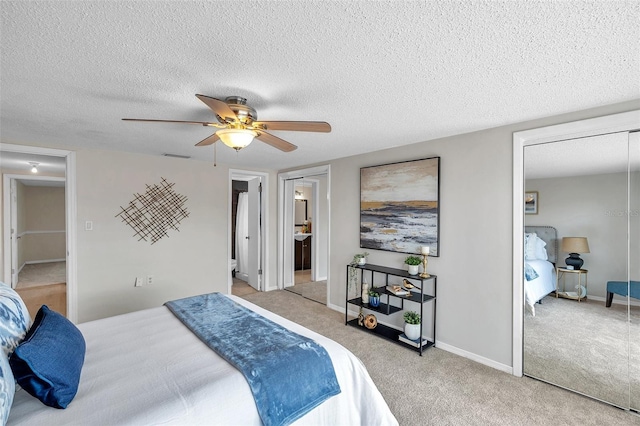 carpeted bedroom with connected bathroom, a textured ceiling, a ceiling fan, baseboards, and visible vents