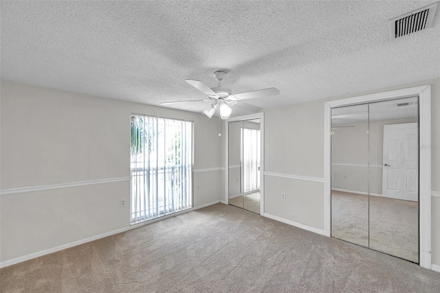 unfurnished bedroom featuring baseboards, carpet, a ceiling fan, and visible vents