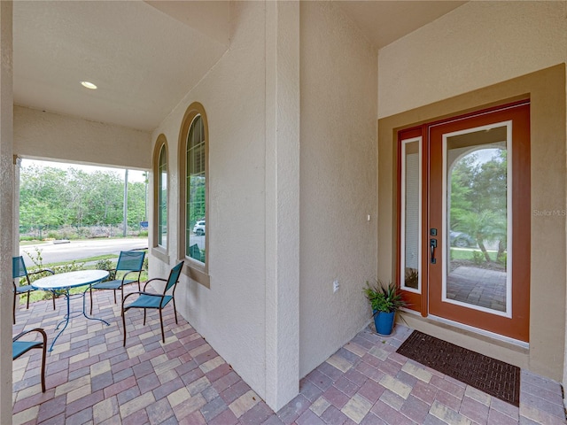 view of exterior entry featuring a porch and stucco siding