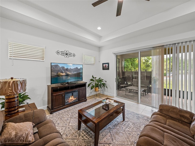 living area with a ceiling fan, a glass covered fireplace, light tile patterned floors, baseboards, and recessed lighting
