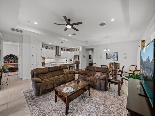 living area with a raised ceiling, light tile patterned floors, ceiling fan with notable chandelier, visible vents, and recessed lighting