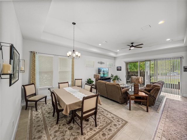 dining area with ceiling fan with notable chandelier, light tile patterned floors, baseboards, and a raised ceiling