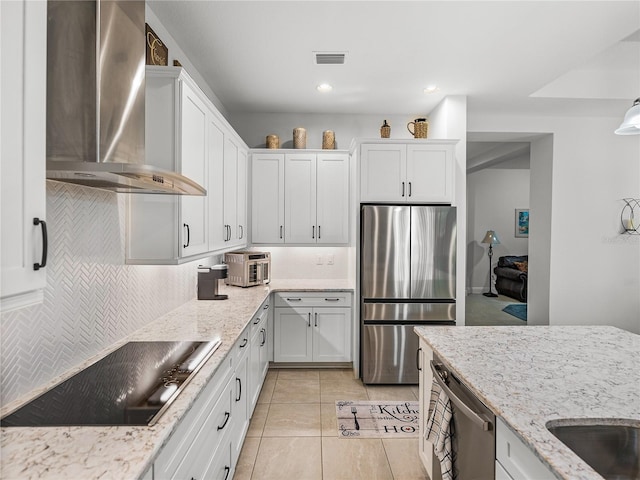 kitchen with wall chimney range hood, decorative backsplash, stainless steel appliances, and visible vents
