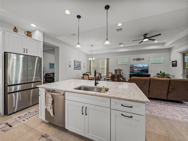 kitchen with a raised ceiling, a sink, open floor plan, and appliances with stainless steel finishes