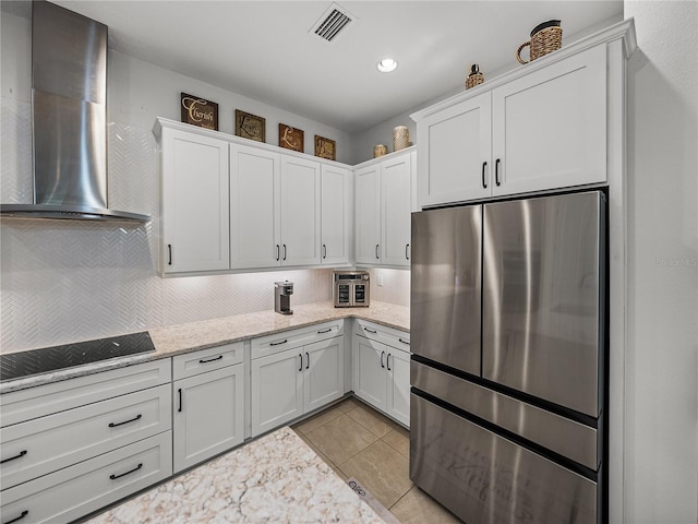 kitchen featuring white cabinets, wall chimney exhaust hood, black electric stovetop, backsplash, and freestanding refrigerator