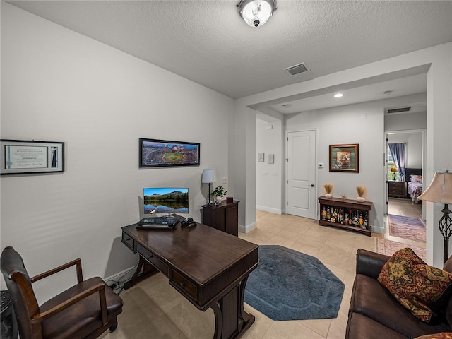 home office with light tile patterned flooring, a textured ceiling, baseboards, and visible vents