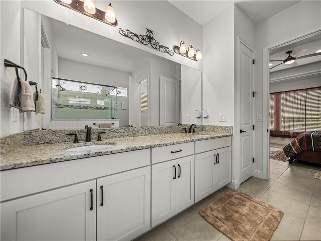 ensuite bathroom featuring tile patterned floors, a sink, a stall shower, and double vanity