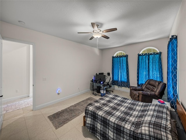 bedroom with tile patterned floors, ceiling fan, baseboards, and a textured ceiling