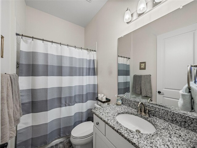bathroom featuring toilet, a shower with shower curtain, and vanity