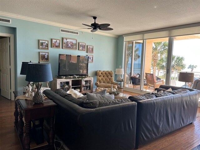 living room with wood finished floors, visible vents, ornamental molding, a textured ceiling, and ceiling fan