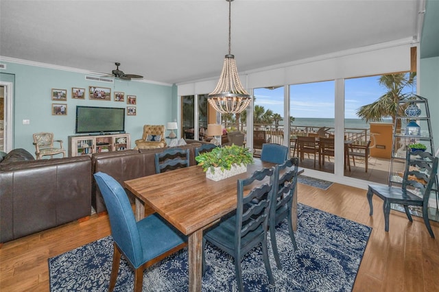 dining area with wood finished floors, crown molding, and ceiling fan with notable chandelier