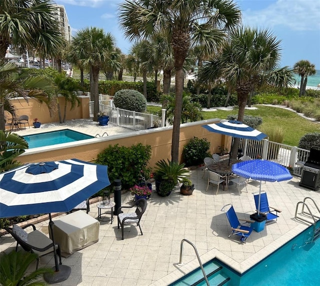 community pool featuring grilling area, a patio area, a fenced backyard, and outdoor dining area