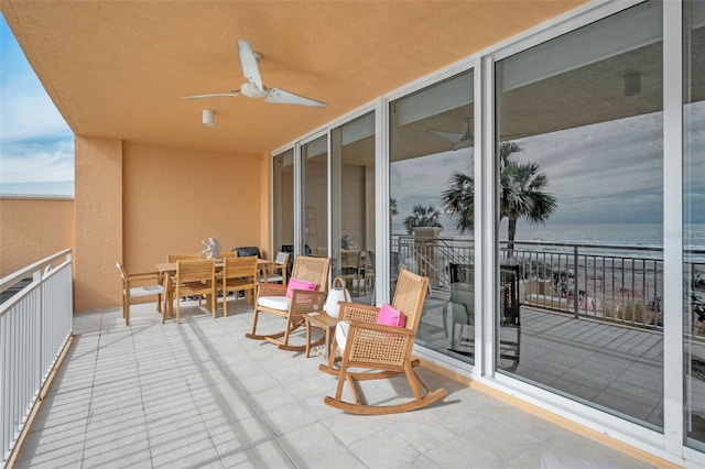 balcony with outdoor dining space, a water view, and ceiling fan
