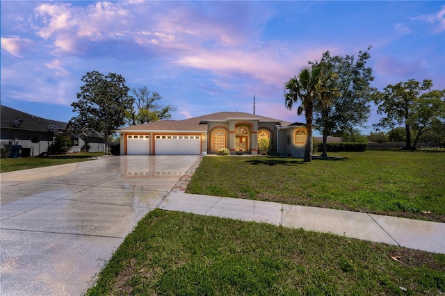 mediterranean / spanish house featuring a front yard, a garage, stucco siding, and concrete driveway