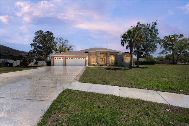 mediterranean / spanish home featuring driveway, a garage, a lawn, and stucco siding