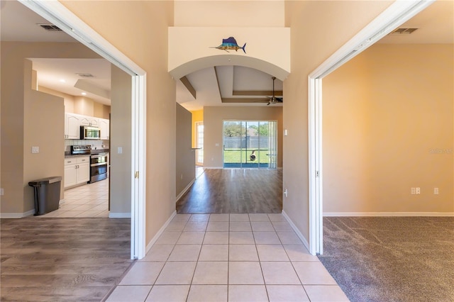 entrance foyer with light tile patterned floors, baseboards, arched walkways, visible vents, and a ceiling fan
