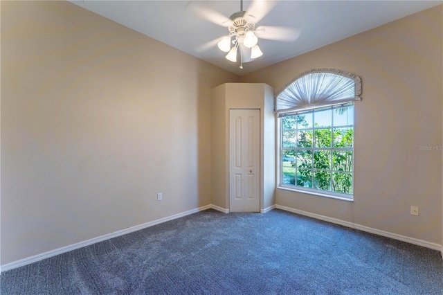 carpeted spare room with a ceiling fan and baseboards