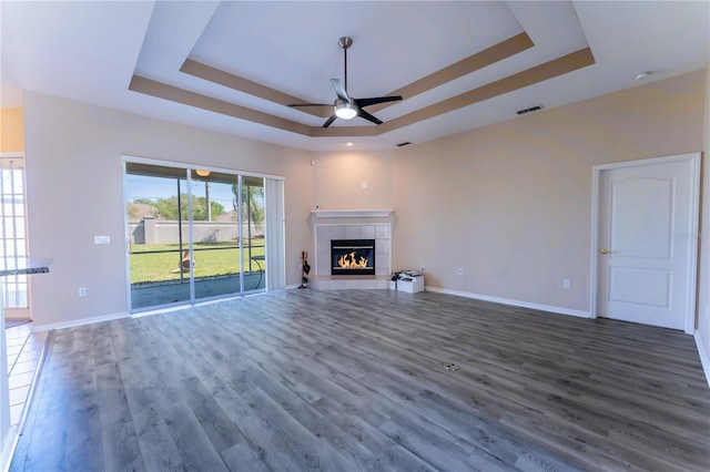 unfurnished living room featuring visible vents, wood finished floors, ceiling fan, and a raised ceiling