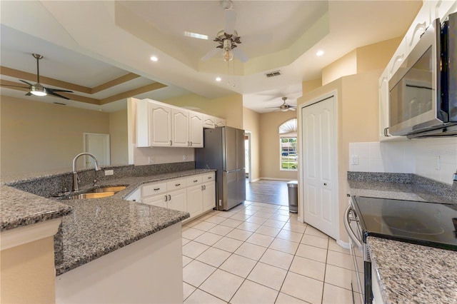 kitchen featuring a sink, a raised ceiling, a ceiling fan, appliances with stainless steel finishes, and visible vents