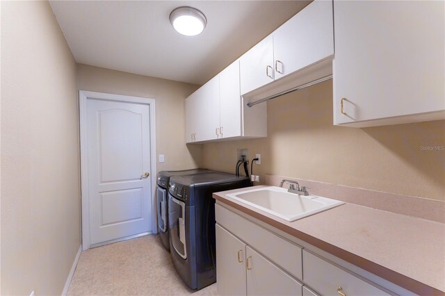 laundry area featuring baseboards, separate washer and dryer, cabinet space, and a sink