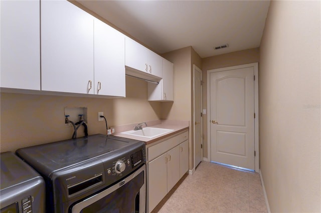 washroom with baseboards, a sink, visible vents, cabinet space, and washer and dryer
