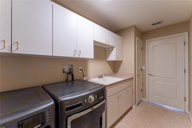 washroom with cabinet space, visible vents, a sink, and washer and dryer