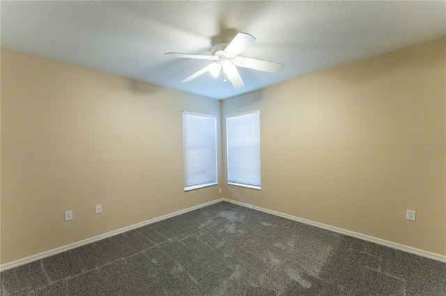 empty room featuring baseboards, dark colored carpet, a textured ceiling, and ceiling fan