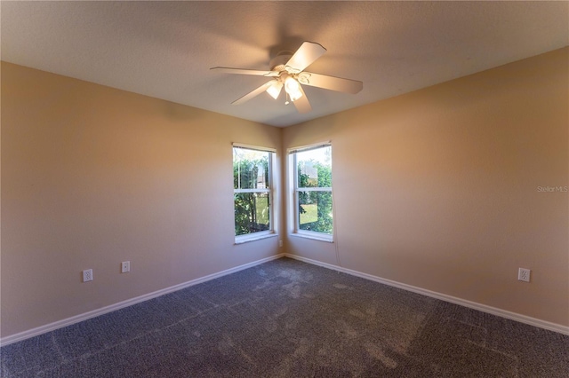 empty room featuring baseboards, a ceiling fan, and dark colored carpet