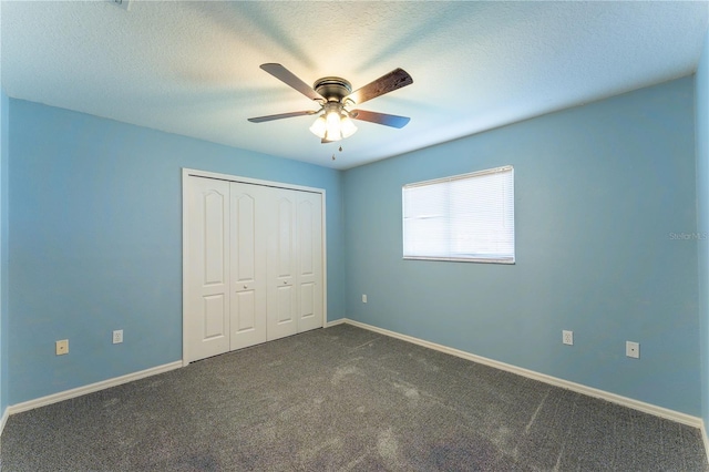 unfurnished bedroom with a closet, a ceiling fan, a textured ceiling, dark colored carpet, and baseboards