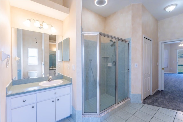 bathroom with toilet, a stall shower, tile patterned flooring, and vanity