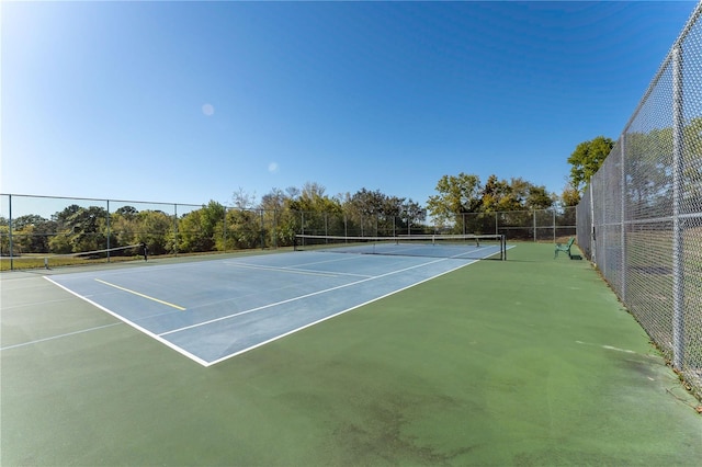 view of tennis court featuring fence and community basketball court