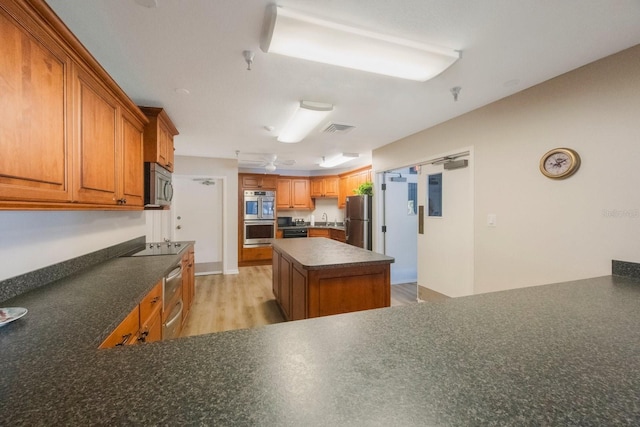 8020 Sailboat Key Blvd S Unit 101, St Pete Beach, FL 33707 - kitchen with stainless steel appliances, dark countertops, a sink, light wood-type flooring, and brown cabinetry