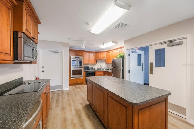 8020 Sailboat Key Blvd S Unit 101, St Pete Beach, FL 33707 - kitchen with black appliances, dark countertops, light wood-style floors, and ceiling fan