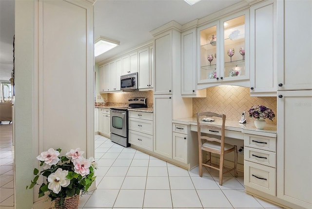 6021 Bahia Del Mar Cir Unit 137, Saint Petersburg, FL 33715 - kitchen featuring light countertops, stainless steel appliances, backsplash, light tile patterned flooring, and glass insert cabinets