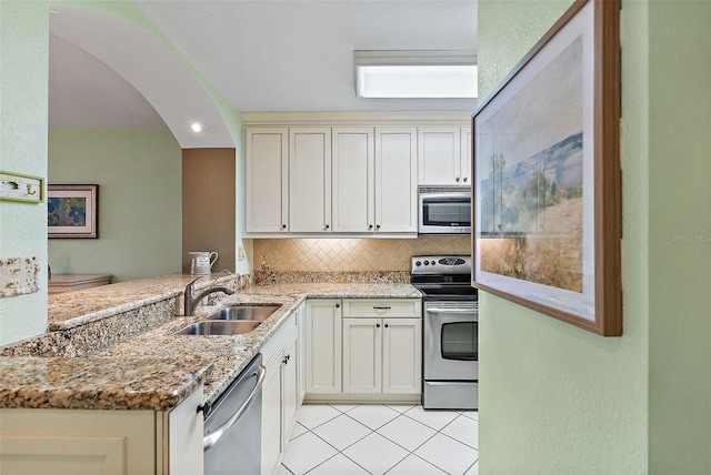 6021 Bahia Del Mar Cir Unit 137, Saint Petersburg, FL 33715 - kitchen with light stone countertops, stainless steel appliances, tasteful backsplash, arched walkways, and a sink
