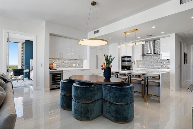 kitchen with white cabinetry, wine cooler, double oven, backsplash, and modern cabinets