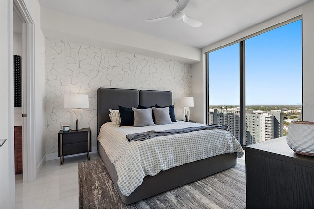 bedroom featuring floor to ceiling windows, a ceiling fan, and an accent wall