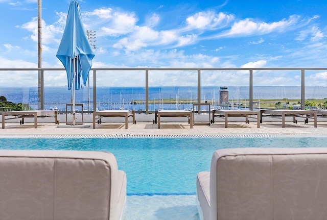 pool featuring a water view and a patio area