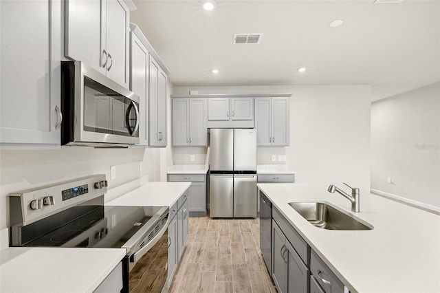 12323 Hearts Ease St, Venice, FL 34293 - kitchen with a sink, appliances with stainless steel finishes, recessed lighting, light wood finished floors, and gray cabinetry