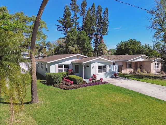 ranch-style home featuring a front lawn, stucco siding, fence, and concrete driveway