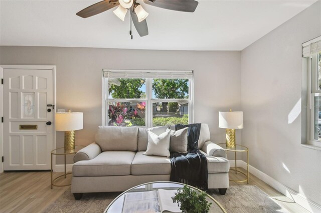 living area featuring baseboards, wood finished floors, and ceiling fan