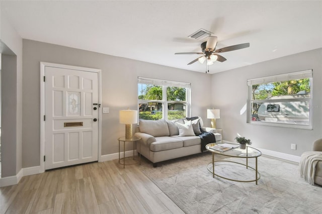 living area featuring a ceiling fan, light wood-style flooring, baseboards, and visible vents