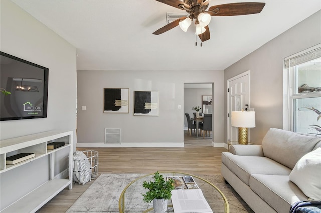 living room with baseboards, visible vents, a ceiling fan, and wood finished floors