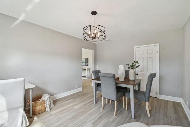 dining area with an inviting chandelier, baseboards, and light wood-type flooring
