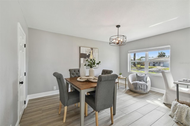 dining room with baseboards, light wood-style floors, and an inviting chandelier