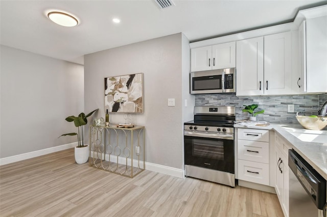 kitchen featuring backsplash, light wood-style flooring, and appliances with stainless steel finishes