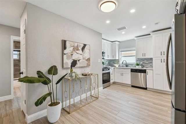 kitchen with light countertops, a sink, stainless steel appliances, visible vents, and decorative backsplash