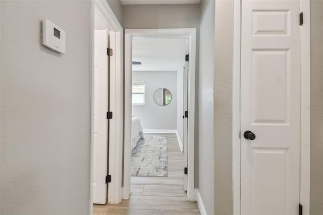 hallway featuring light wood-style floors and baseboards